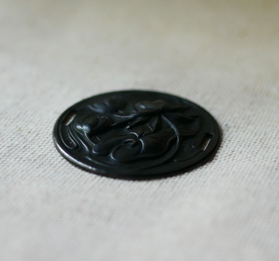 Medaljong i svart metall i relief med sidoband 