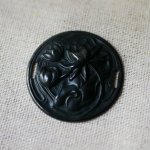 Medaljong i svart metall i relief med sidoband 