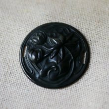Medaljong i svart metall i relief med sidoband 